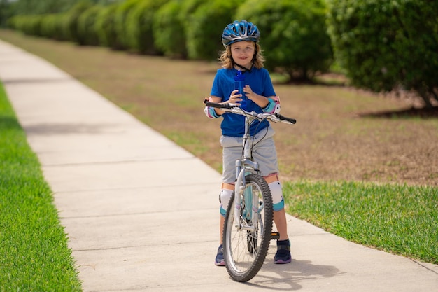 Foto un ragazzino in bicicletta nel parco estivo un bambino guida una bicicletta su un vialetto fuori un bambino in bicicletta