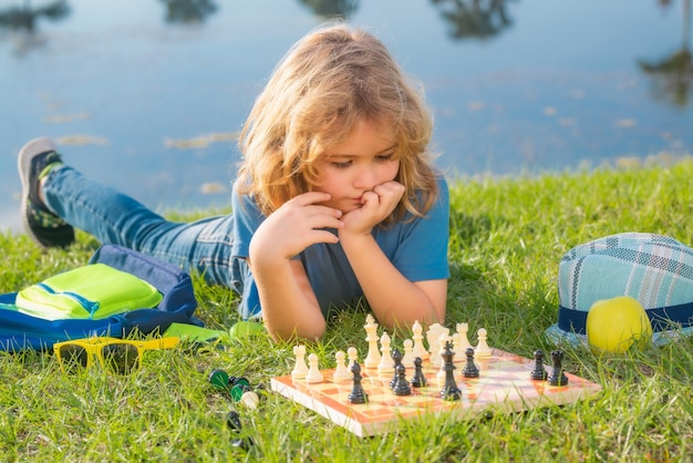 小さな子供のチェスマンがチェス ゲームのチェックメイトをプレイします。春の公園でチェスをする子供