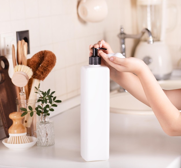 Bambino bambino lavarsi le mani con distributore di sapone in una cucina mockup contenitore bianco