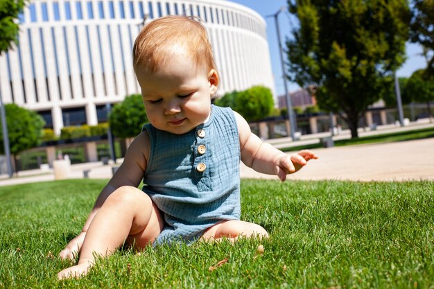 Photo little kid crawls learns to crawl on the green grass in the park in summer