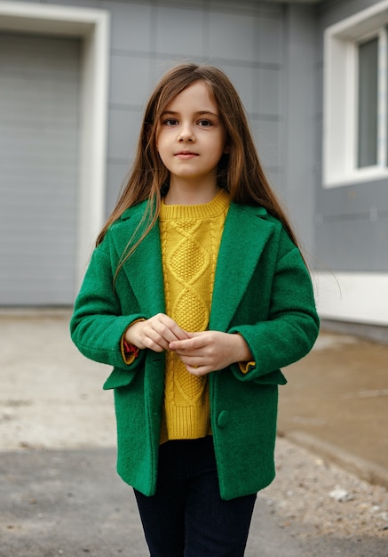 Little kid girl in green coat posing