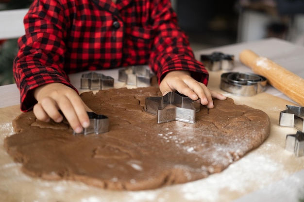 Bambina in pigiama rosso che cucina pan di zenzero festivo in cucina decorata di natale natale c...