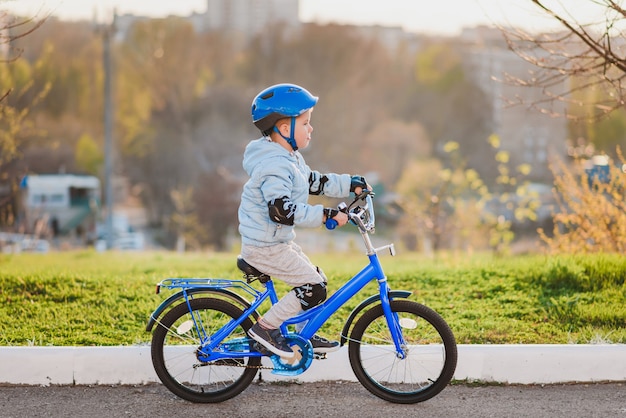 Little kid in helmet rides a bicycle on a sunny day