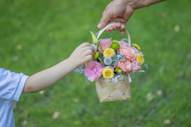 小さな子供と彼のおばあちゃんは、手に美しい混合花のバスケットを持っています