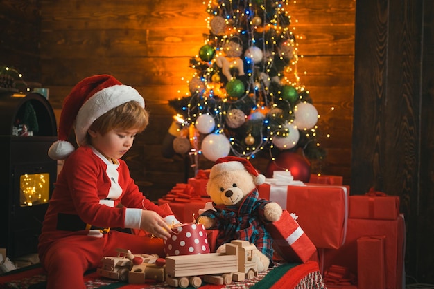 小さな子供は彼の手にクリスマスプレゼントとサンタの服を着ています子供は新年を待っています...