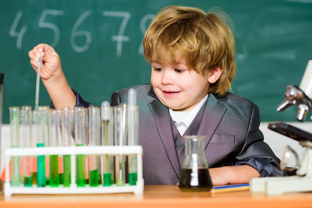 Little kid learning chemistry in school laboratory. Little boy at chemical cabinet. kid in lab coat learning chemistry chemistry lab. Back to school. experimenting with chemical. Scientist at work.