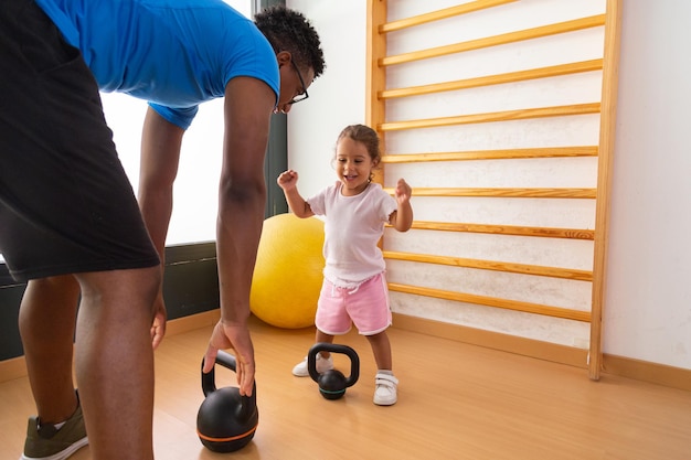 Little kid lifting kettlebell with father