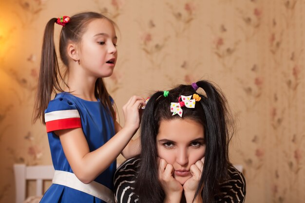 Little kid making hairstyle to her mother.