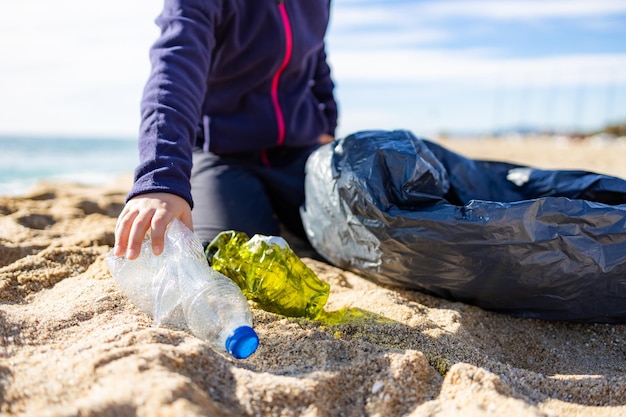 사진 해변에서 플라스틱을 수집하는 작은 아이의 재활용 개념