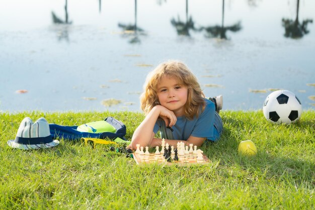 Фото Маленький ребенок играет в шахматы в парке маленький мальчик играет в настольную игру на открытом воздухе думает ребенок мозговой штурм и идея в шахматной игре