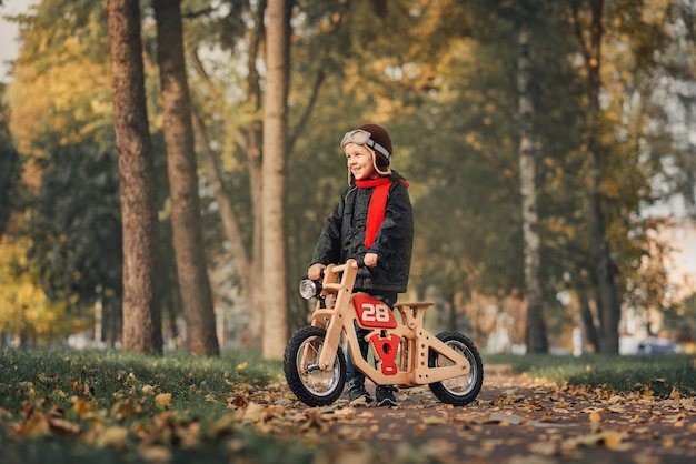 Foto ragazzino in sella a una bici senza pedali in abbigliamento esterno in autunno