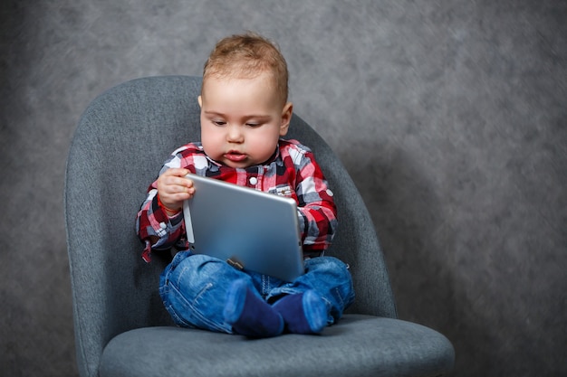 A little kid in a shirt plays with a tablet