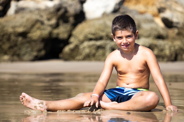 Photo little kid sitting on a rocky beach