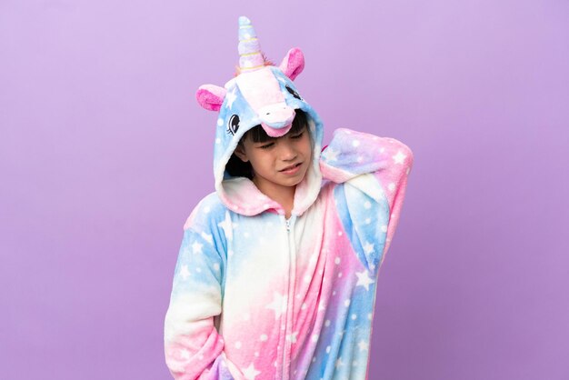 Little kid wearing a unicorn pajama isolated on purple background with neckache