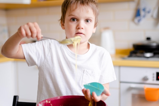 Little kid years old cooks cupcakes in light kitchen at home little boy uses silicone baking molds