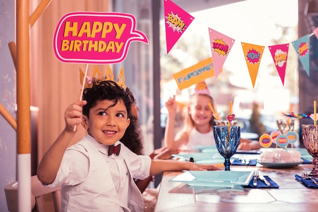 Bambini piccoli che partecipano a una festa di compleanno e si siedono al tavolo