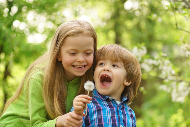 Little kids blowing dandelion toddler age summer at countryside happy childhood and country life