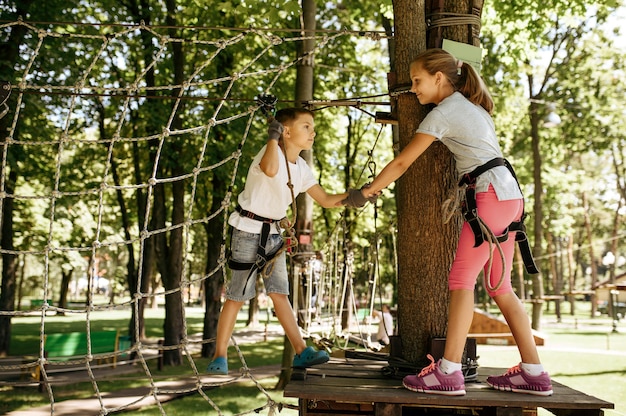 little kids climbs on net in rope park