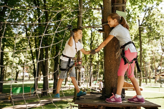 Little kids climbs on net in rope park