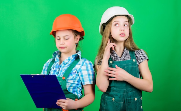 Little kids in helmet with tablet Labor day 1 may small girls repairing together in workshop Foreman inspector Repair school project helmet and tablet all you need for work