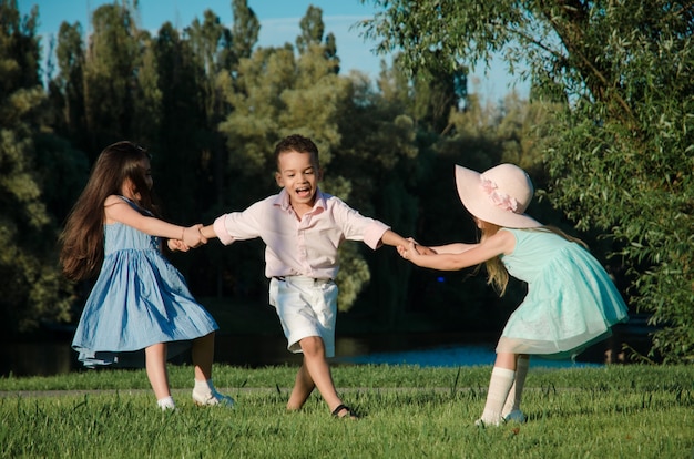 The little kids playing around on the lawn. two girls and a boy