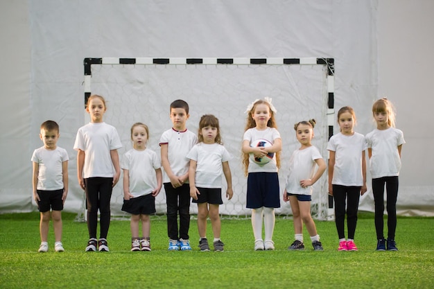 屋内でサッカーをしている小さな子供たち子供たちは列に並んでいます