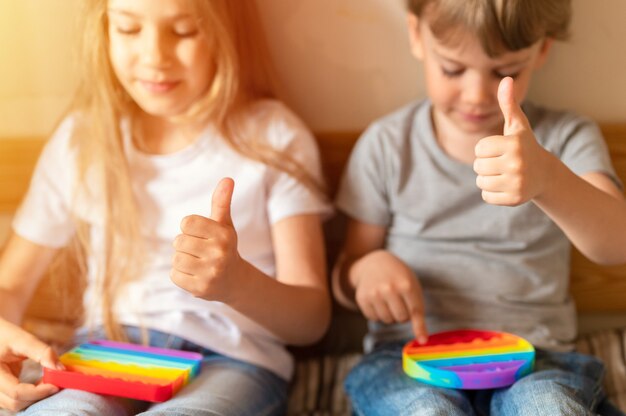 I bambini piccoli giocano con il pop sensoriale antistress per bambini o semplici giocattoli con fossette e pollice in su