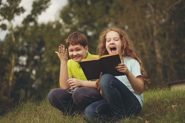 Little kids reading the book outdoors. Education concept.