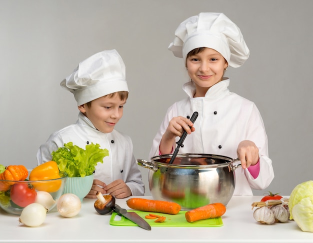 Little kids at a table with vegetables