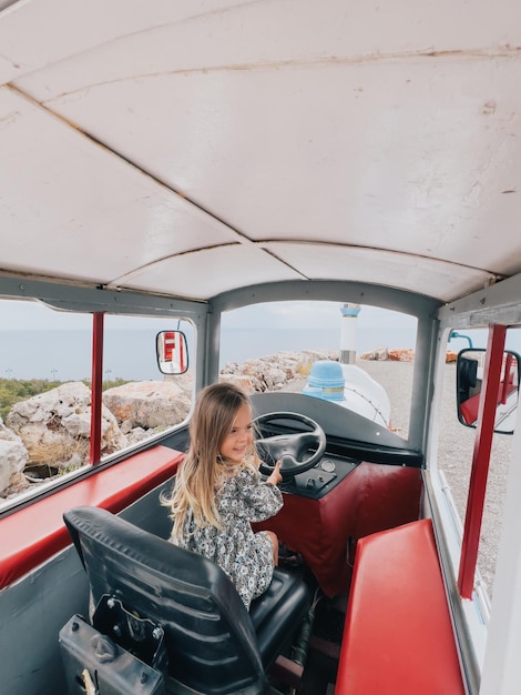 Little laughing girl sitting behind the wheel of a tractor