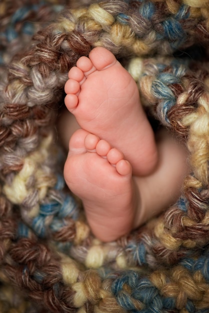 Photo little legs baby in a grey scarf.