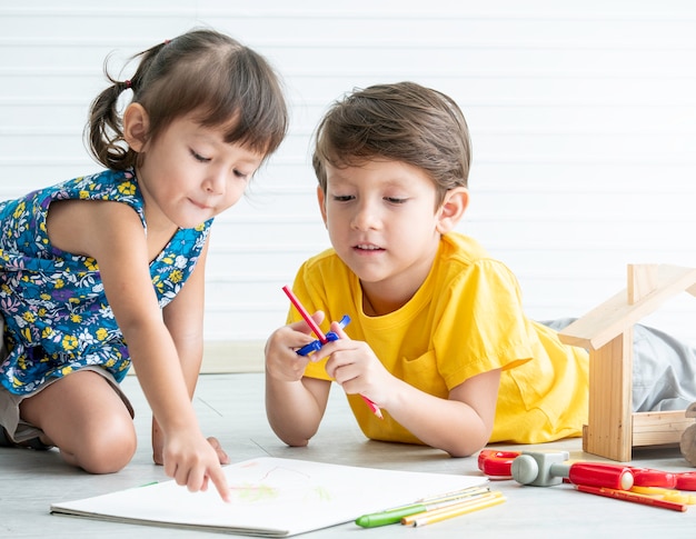 Piccolo ragazzo adorabile e ragazza che giocano i giocattoli sul pavimento, giochi educativi per i bambini. concetto della sorella e del fratello.