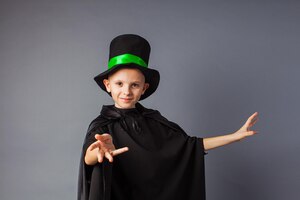Photo little magician does tricks little boy wears costume magician and magic hat