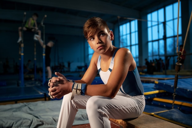 Little male gymnast training in gym, flexible and active