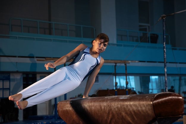 Piccola ginnasta maschio allenamento in palestra flessibile e attiva