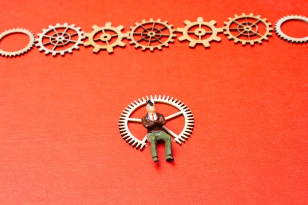 Photo little man figurine and wooden gear wheels in view