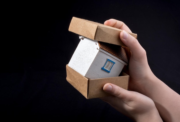 Little model house in hand in a paper box