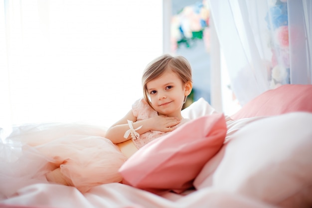 Photo little nice girl in dress lying on bed