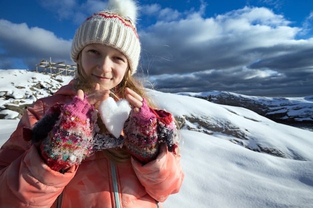 ノルウェーの少女は、雪の心を手に持っています。楽しい冬。ノルウェー