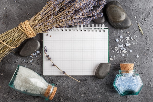 Little notebook, lavender, mineral sea salt and zen stones on a gray stone background. top view