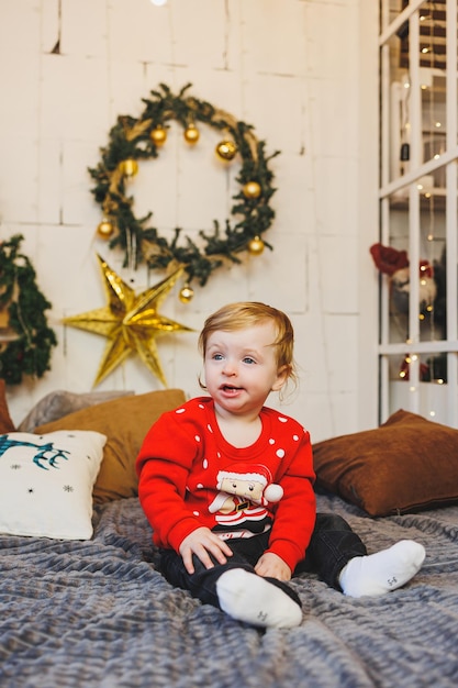 little oneyearold boy near the Christmas tree an idea for a children's photo for the new year studio New Year decoration Christmas gifts red children's festive costume