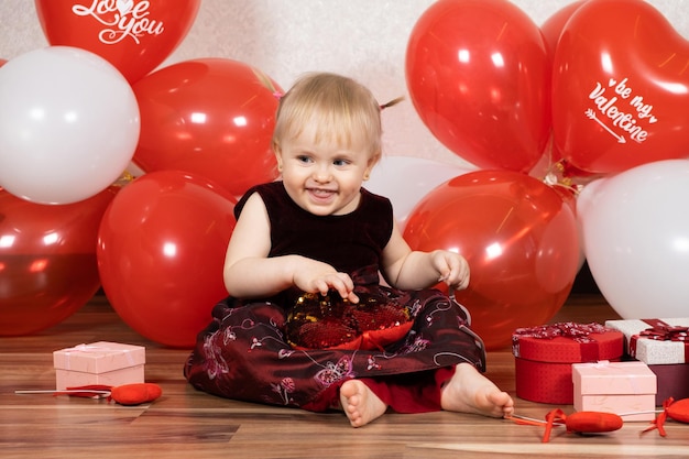 A little oneyearold girl plays with heart pillow on Valentine's Day