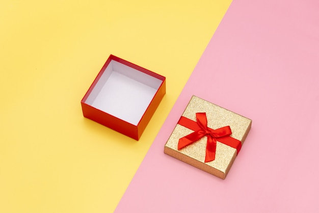 Little open gift box on pink and yellow backgrounds.