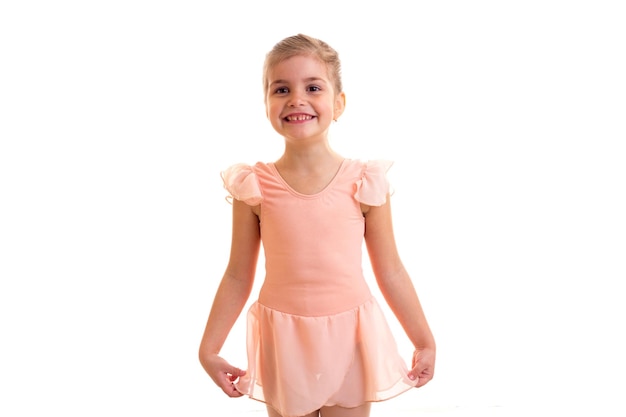 Little optimistic girl in pink dress dancing on white background in studio