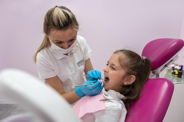 little patient grimaces during an examination of the oral cavity by a female dentist