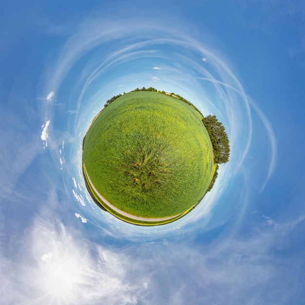 Piccolo pianeta vista sferica in un campo vicino a una strada con colza in una giornata di sole