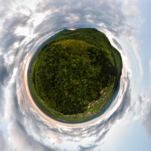 Little planet with dark mountain hills covered with green mixed pine and lush forest.