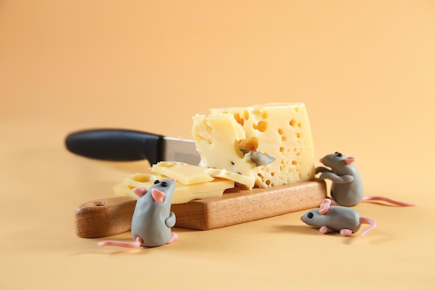 小さな粘土の灰色のネズミがチーズを切る