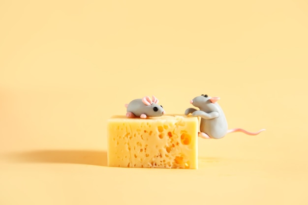 Little plasticine mice and a piece of cheese with holes Beige background