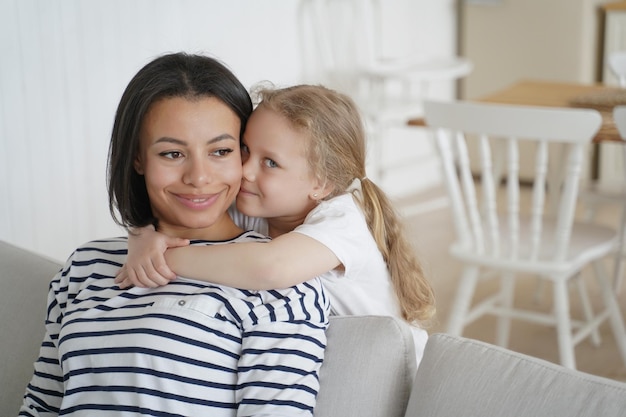 Little preschool daughter cuddling foster mother showing love enjoying hugs together at home